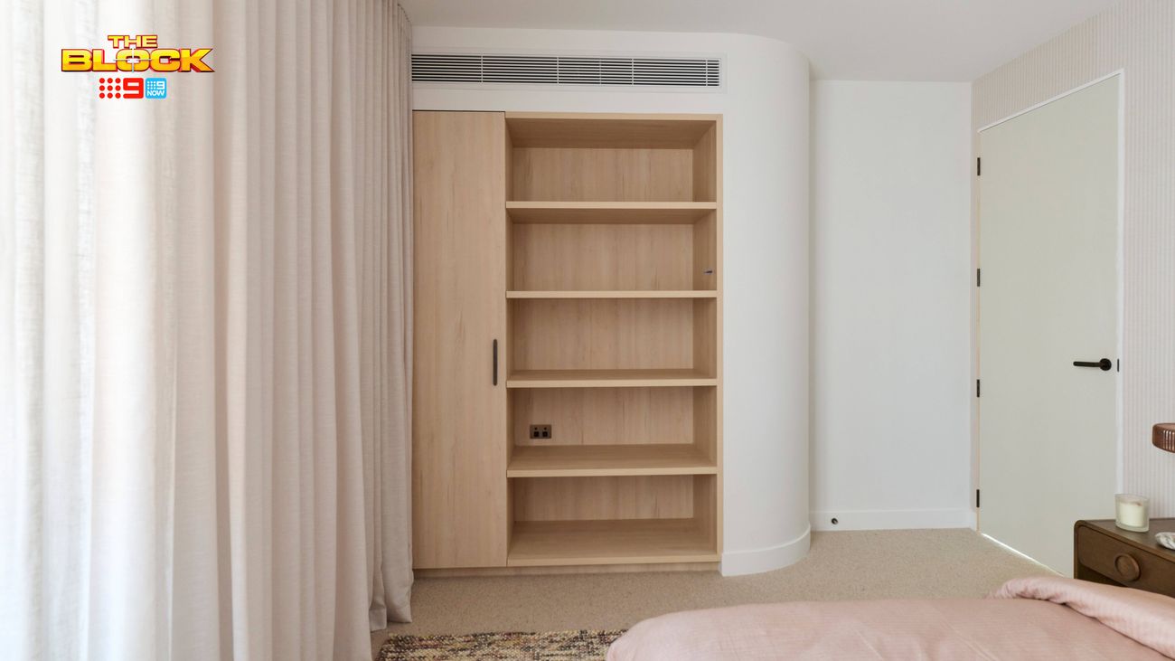 Contemporary bedroom featuring built-in timber shelving, floor-to-ceiling curtains, soft pink bedding and neutral décor.