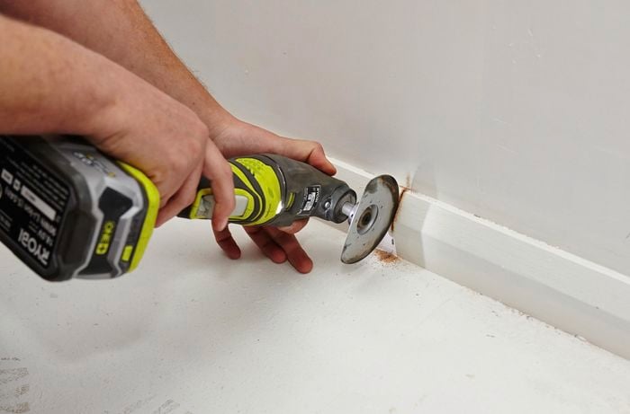 Person using handsaw to cut off skirting board.