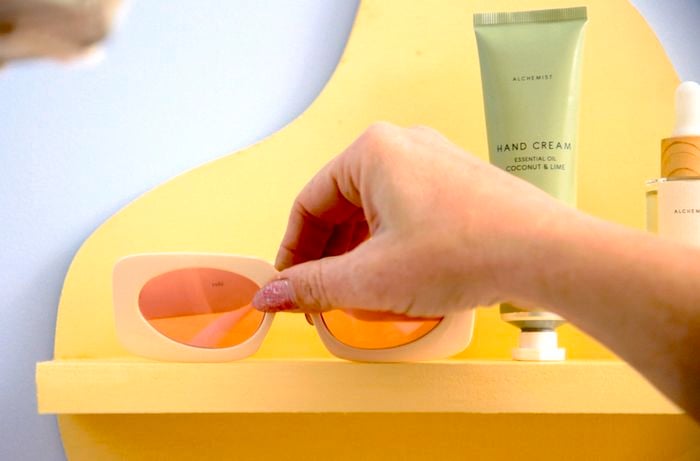 A person adding finishing touches to a new painted shelf.