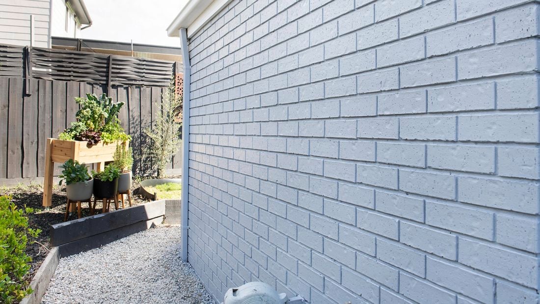 Blue brick wall and planter box, fence in background.