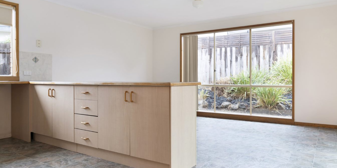 Old kitchen with timber cupboards and tiled floors.