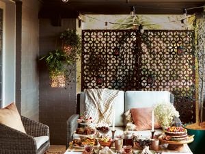 Small outdoor patio showcasing privacy screen, outdoor lounge and decorative lighting.