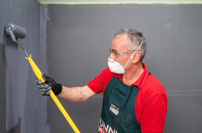 Bunnings team member wearing a mask while applying membrane to a wall