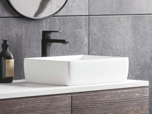A bathroom with a mirror hanging on the wall, a light hanging from the ceiling and a basin with cupboards under it.