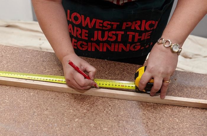 A length of timber being measured and marked for cutting using a pencil and tape measure