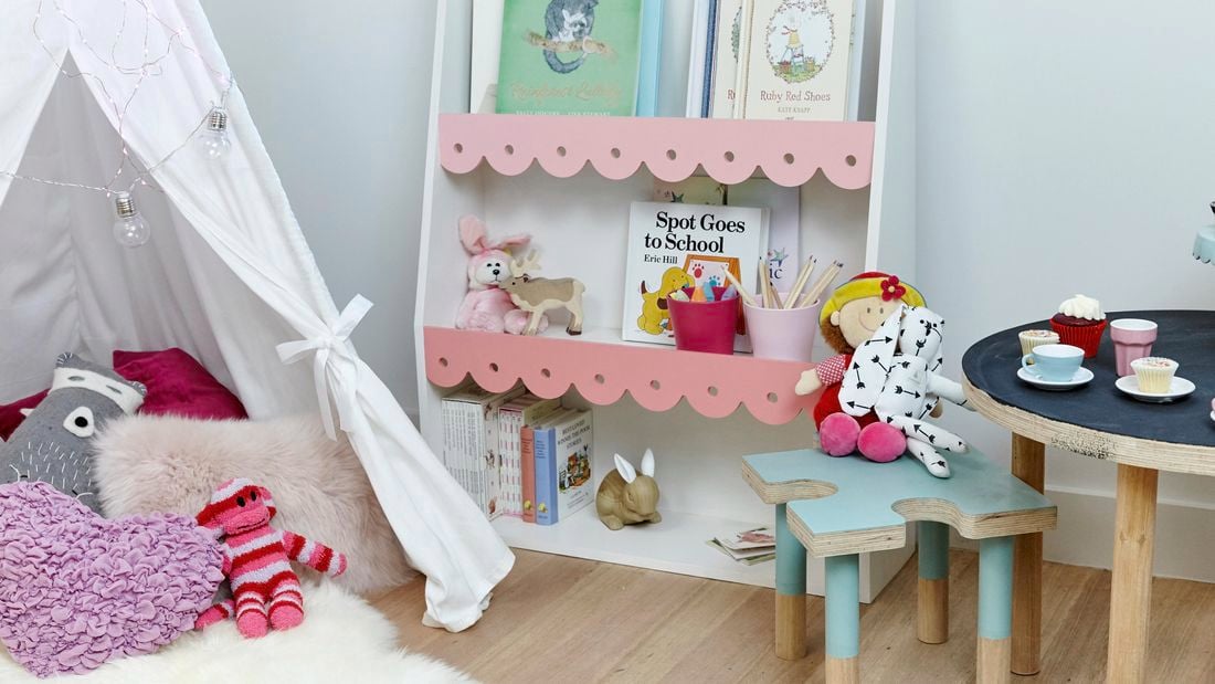 A decorated bookshelf painted pink and white in a child's bedroom