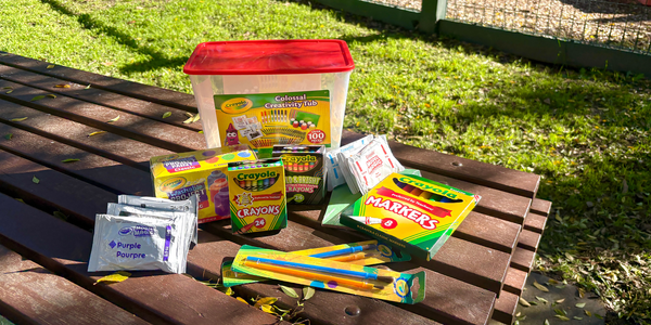 Assortment of Crayola art supplies, including markers, crayons, paint, brushes and creativity tub, displayed on an outdoor table.
