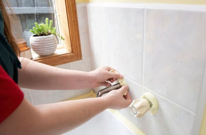 Cleaning wipes being used to clean around bath fittings