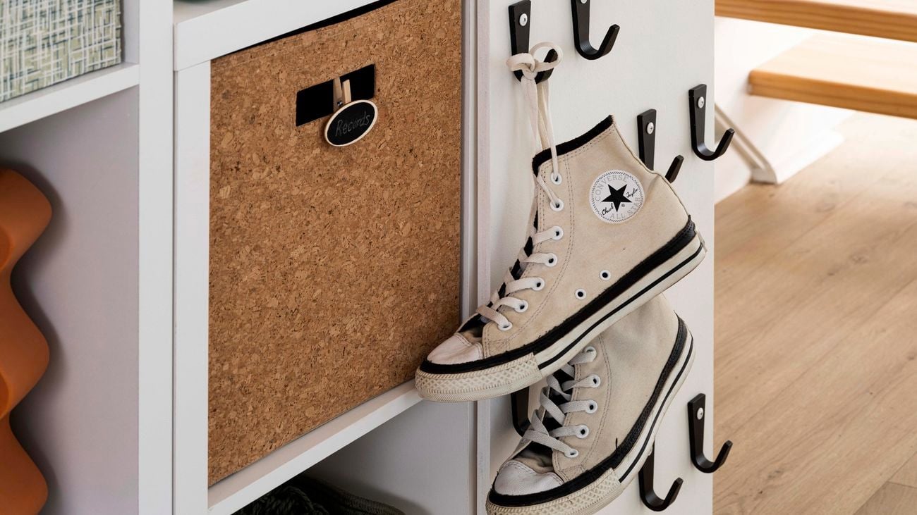 Shelving unit underneath a staircase with converse runners hanging on it, record player and a hat on it