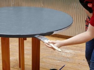 Person painting a round table.