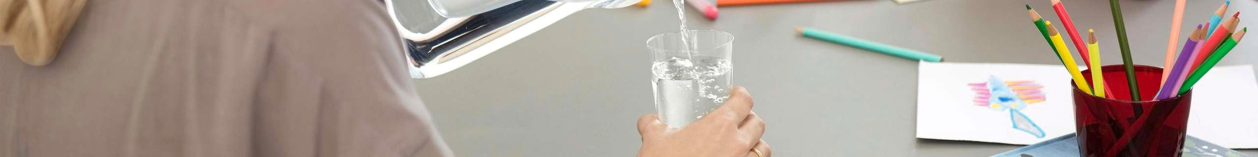 a family on a table with woman pouring water in a glass
