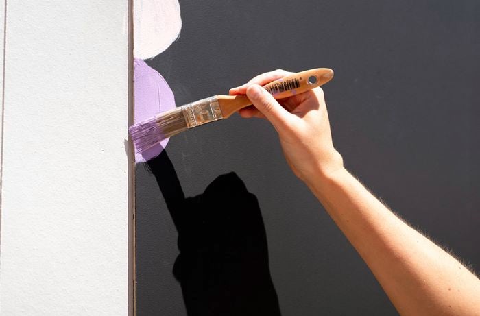 A person is using a fine brush to create a decorative border around the edge of the board.