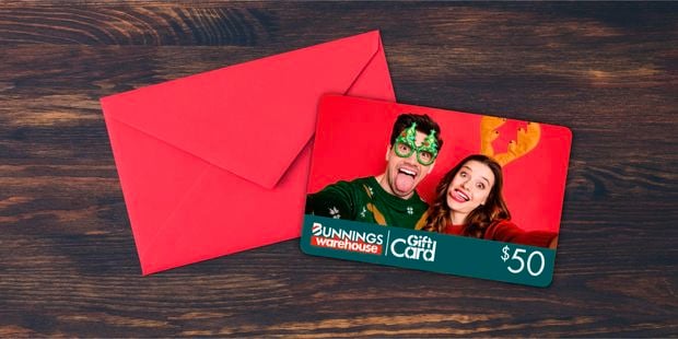 Man and woman in christmas attire on a photo gift card on a wooden table with envelope