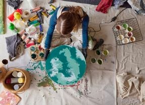 Bella in an art studio holding finished paint pour artwork