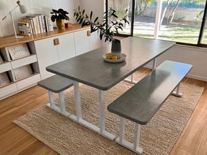 A cement-look dining table in a living room, a vase and two lemons on top of it.