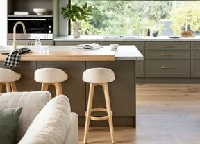 Kitchen with marble benchtop with bar stools and a couch in front of it.