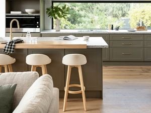 Kitchen with marble benchtop with bar stools and a couch in front of it.