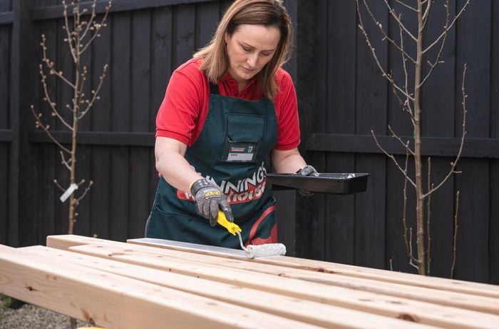 person painting timber post with paint roller
