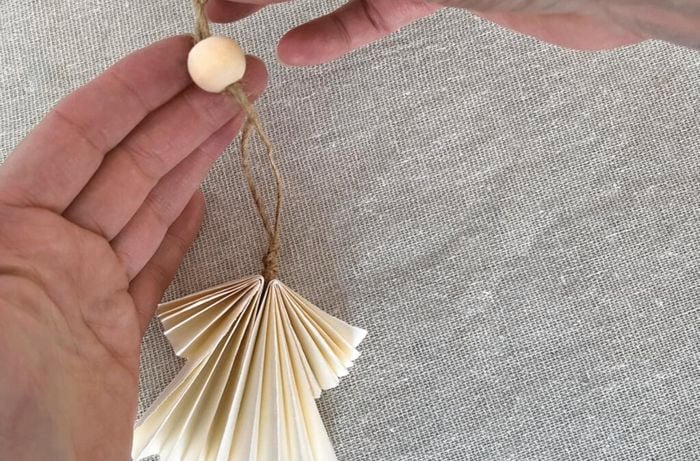  Hands attach bead to piece of twine