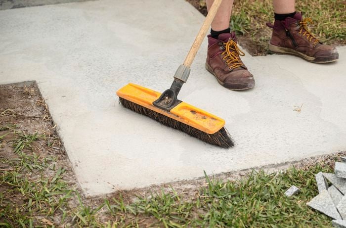 A person sweeping the concrete path.