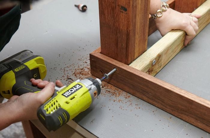 Person screwing wooden table parts together.