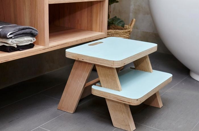 Blue wooden step stool in front of bathroom vanity unit.