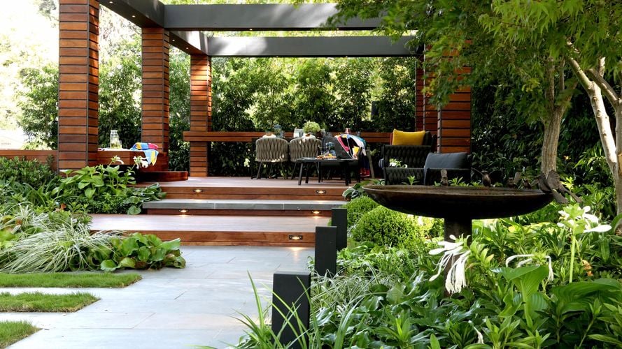 Outdoor gazebo with decking in an outdoor area surrounded by trees.