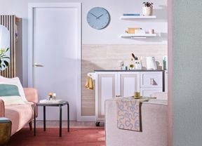 A front-on image of a home showing a kitchen and lounge area decked out in light colour tones.