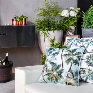 Outdoor furniture with cushions and plants in the background