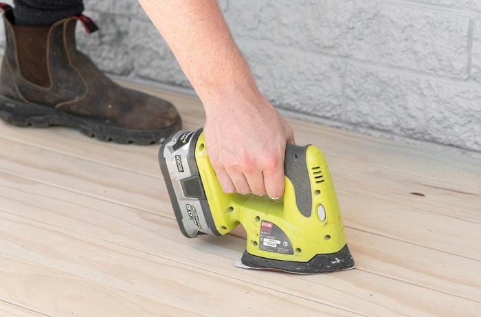Person sanding a deck.