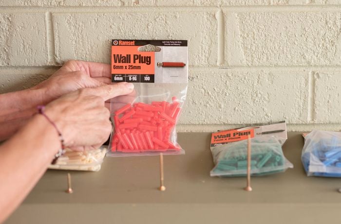 A person holding wall plugs and screws