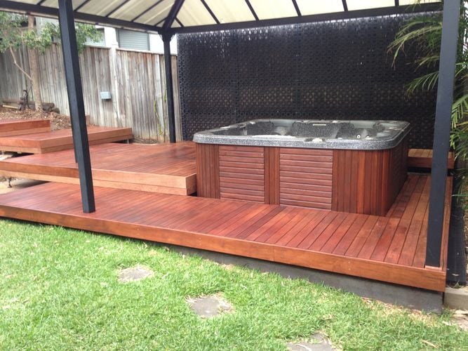 Tiered decking leading under a pergola to an outdoor spa