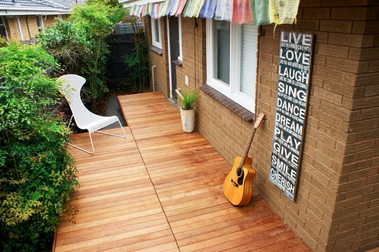 A narrow back deck with a chair, guitar and inspirational poster