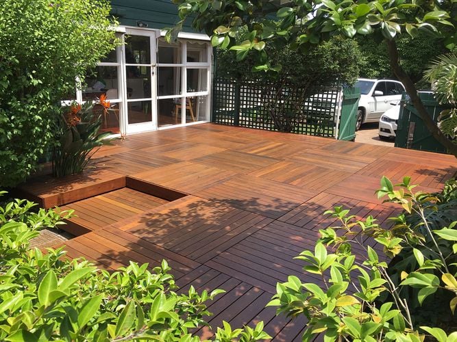 Crosshatched deck amongst bushes with a gate leading to a carpark