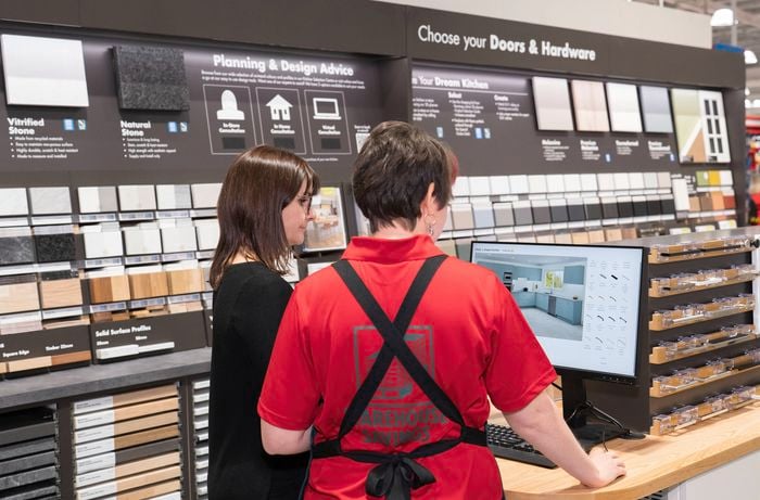 A Bunnings Team Member is assisting a customer with kitchen planning to make selections.