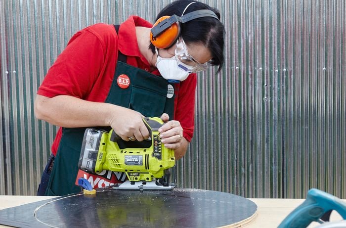 A person using a jigsaw to cut a large circle out of formply