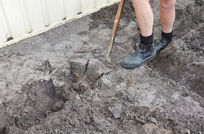 A person digging a trench with a shovel