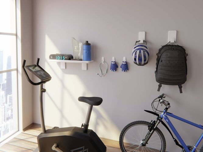 3M Command Hooks and a Command Shelf used to organise cycling gear, including a helmet, gloves and backpack, beside an exercise bike and bicycle.