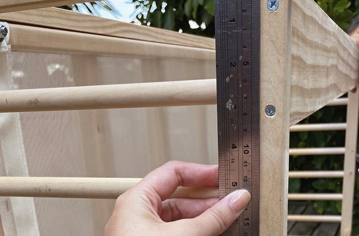 Person using ruler to measure slat of wood on cot