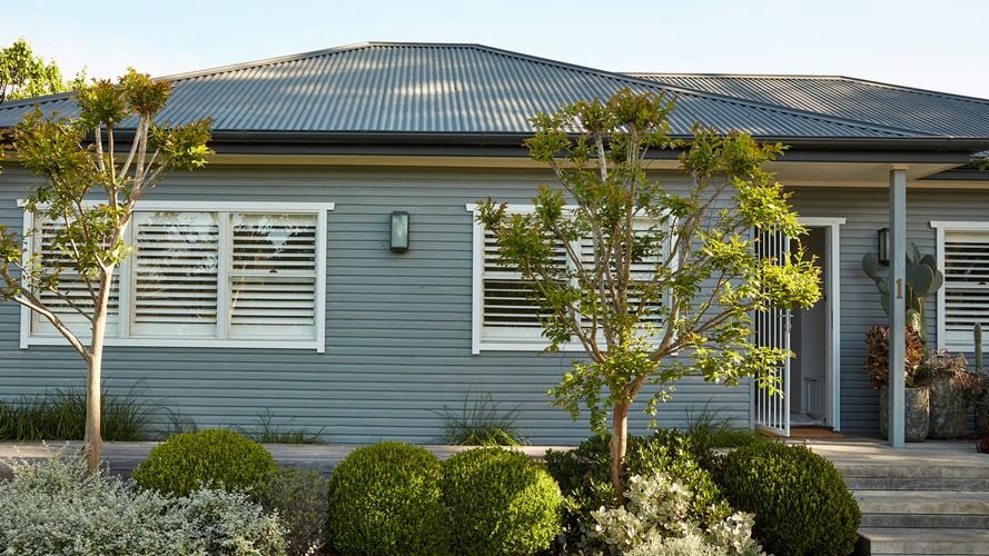 Exterior of a grey coloured weatherboard home with greenery used to display energy saving tips