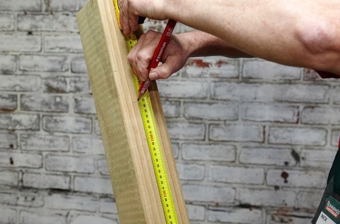 Person using measuring tape to make a mark on piece of timber.