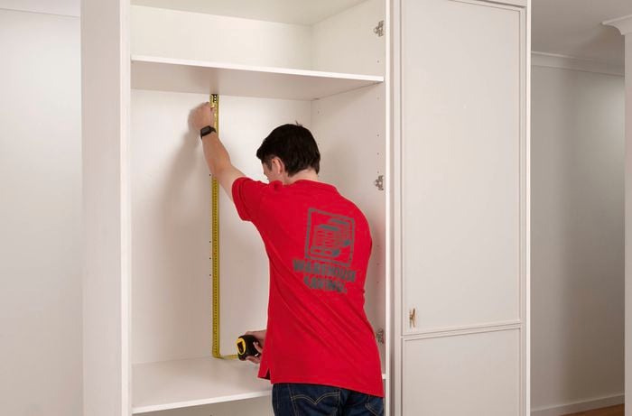 A Bunnings team member is measuring the dimensions of the wall space