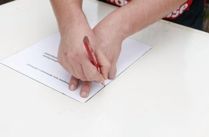 A person tracing around a template on a door with a pencil