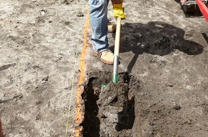 A shovel being used to dig into earth for a foundation
