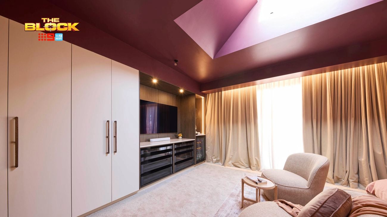Modern bedroom with plum ceiling, large wardrobes, TV unit, beige armchairs, and floor-to-ceiling curtains.