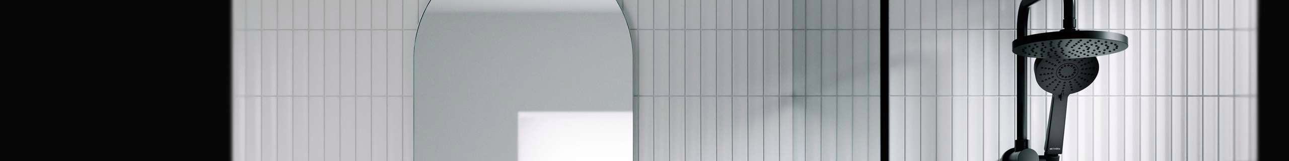 Black shower head and arch mirror on tiled walls.