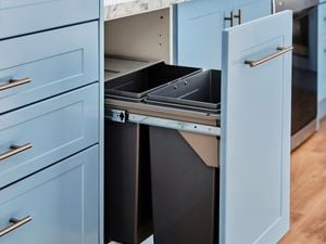 Blue cabinets and pull out bin in kitchen.