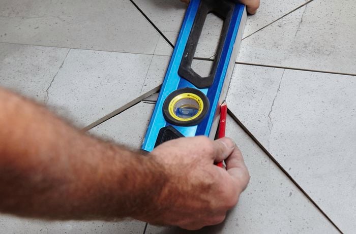 A person marking tiles using a spirit level