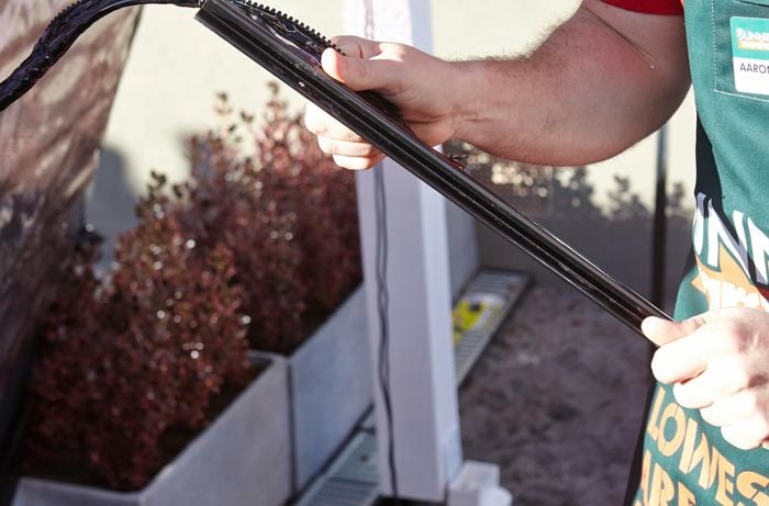 A person inserting the edge of a bistro blind into a wall anchor strip
