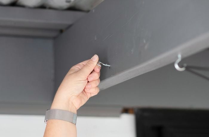 A Bunnings team member securing a screw in a patio roof beam